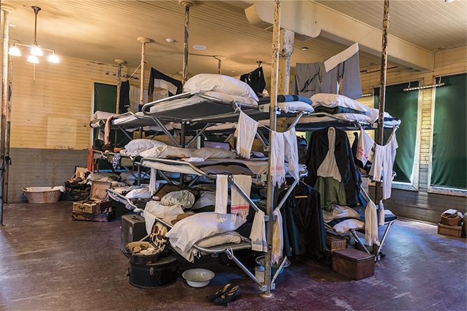 Enlargeable photo of bunk beds with three beds in each and personal items hanging off them