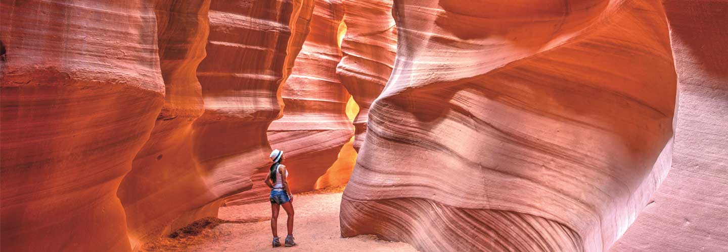 Photo of a person standing in the middle of large rock formation with lots of curvature